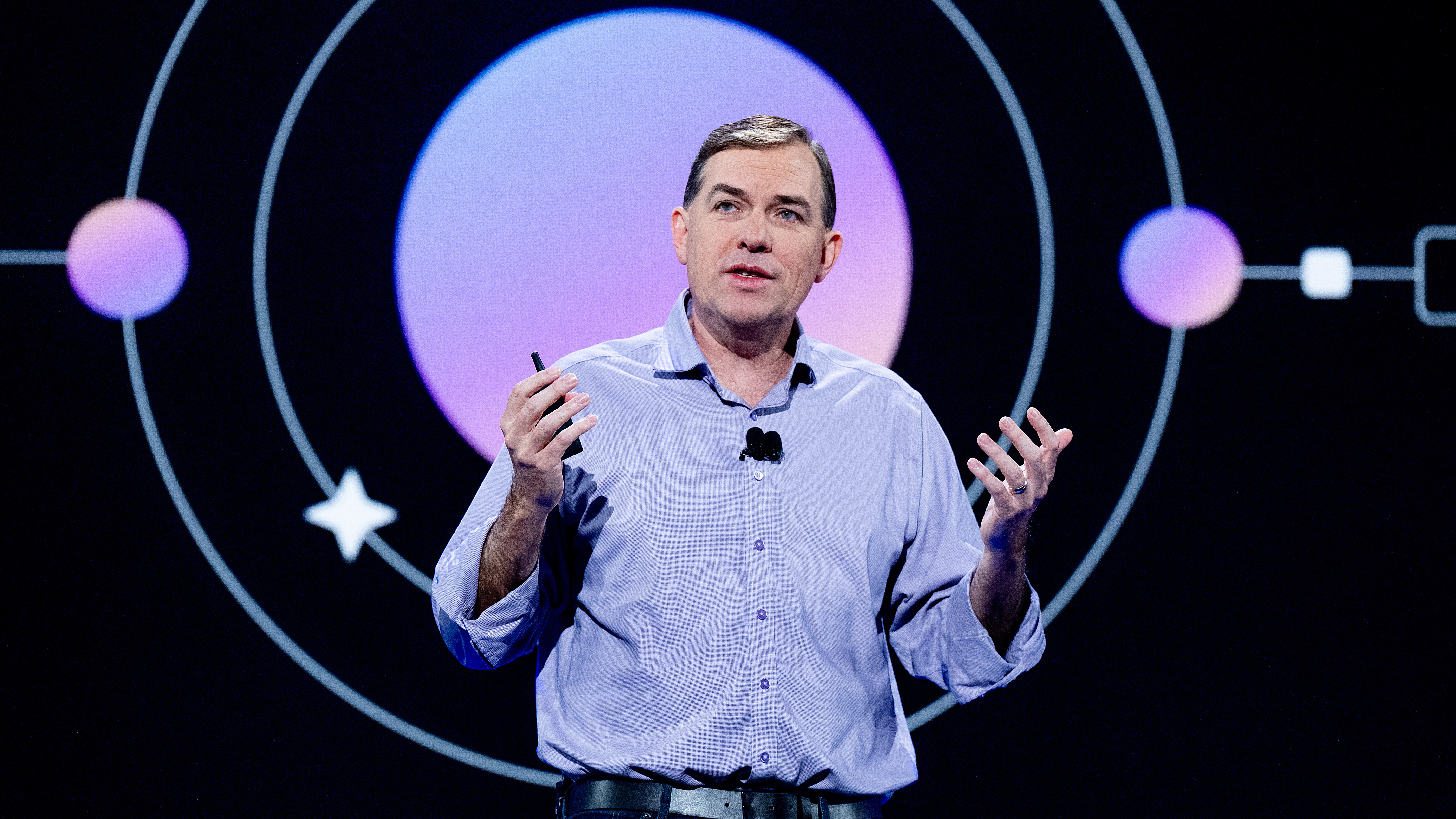 Matt Garman, Keynote speaker and AWS CEO, gesturing on stage with futuristic circular backdrop